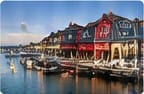 Red and gray waterfront buildings along a wharf with boats